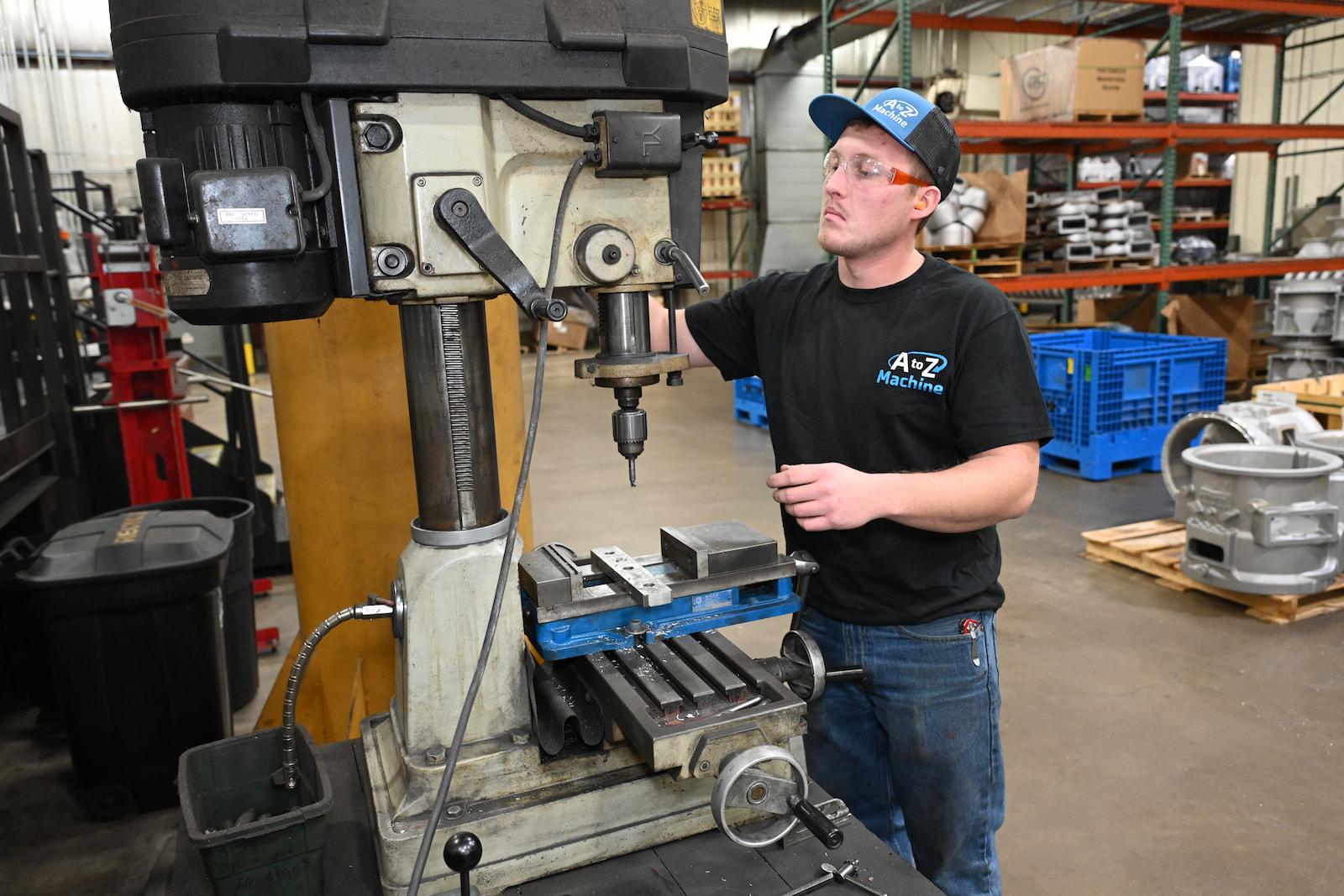 A man is engaged in using a drill press