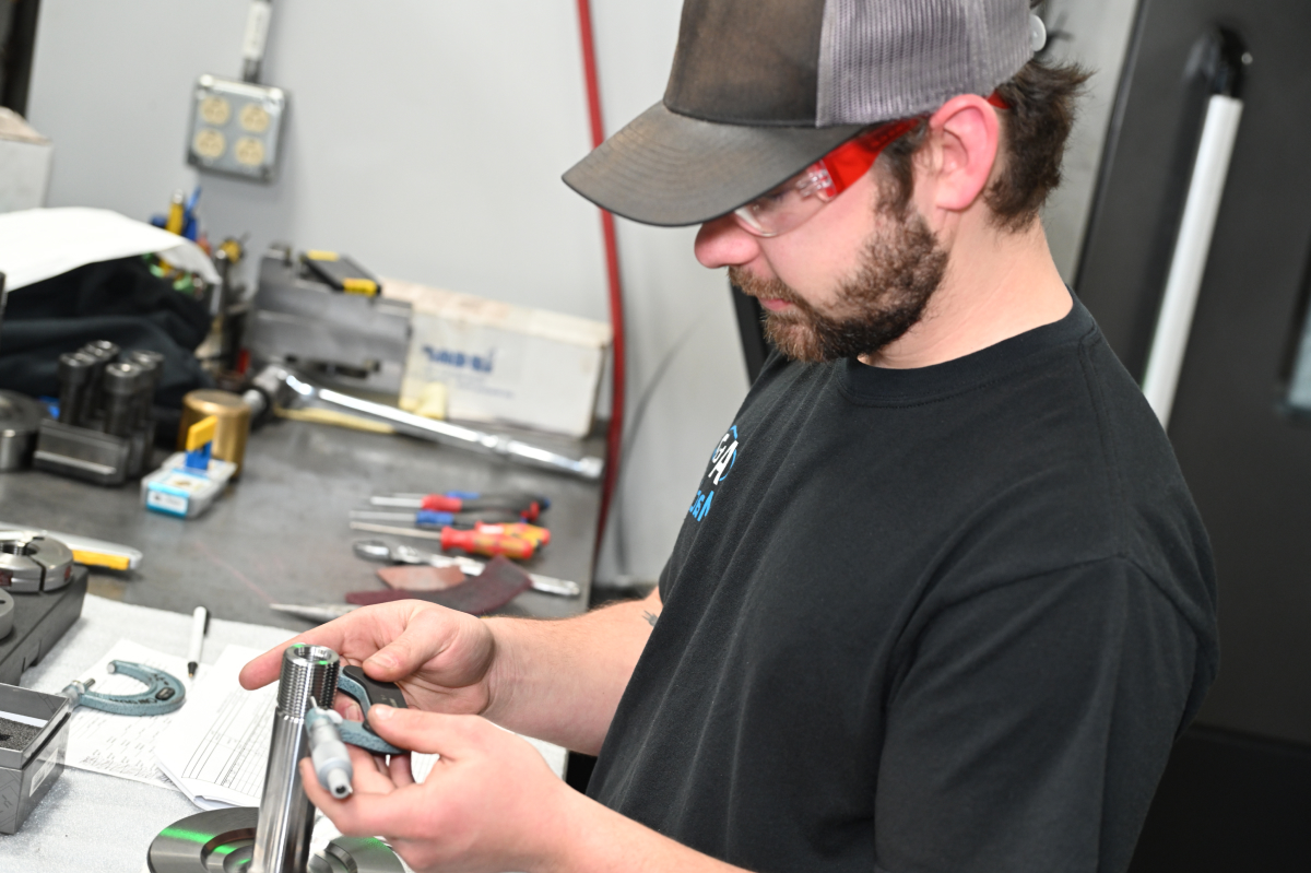 an A to Z Machine employee quality checking a custom made part